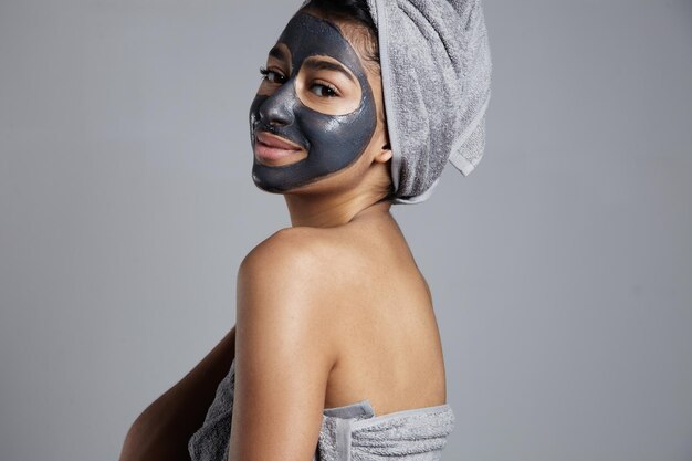 Vrouw met handdoek ingeschakeld camera draagt gezichtsmasker
