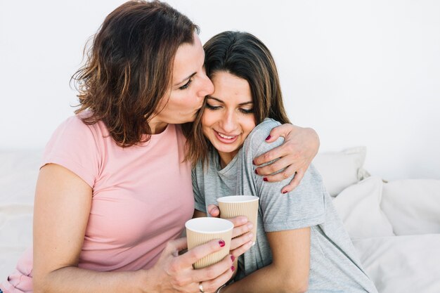 Vrouw met hete drank kussende vrouw