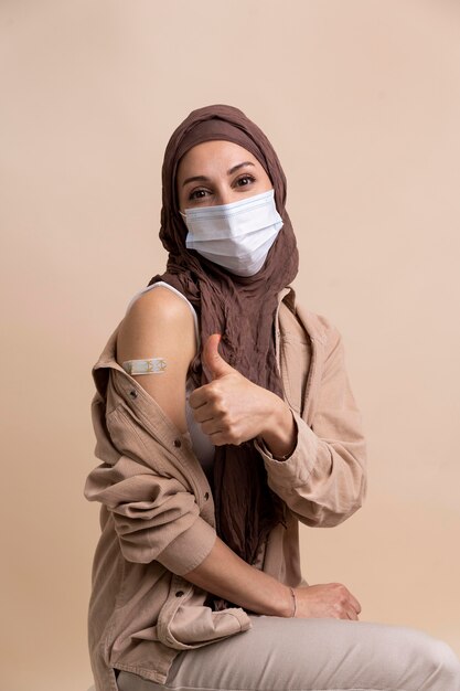 Vrouw met hijab die sticker op arm laat zien nadat ze een vaccin heeft gekregen