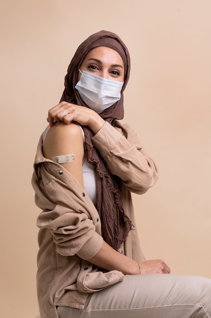 Vrouw met hijab die sticker op arm laat zien nadat ze een vaccin heeft gekregen