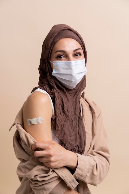 Vrouw met hijab die sticker op arm laat zien nadat ze een vaccin heeft gekregen