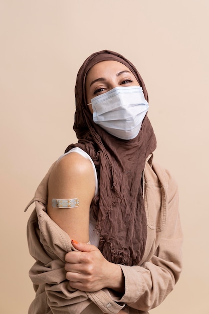 Vrouw met hijab die sticker op arm laat zien nadat ze een vaccin heeft gekregen