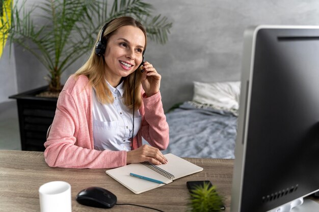 Vrouw met hoofdtelefoon die aan computer werkt