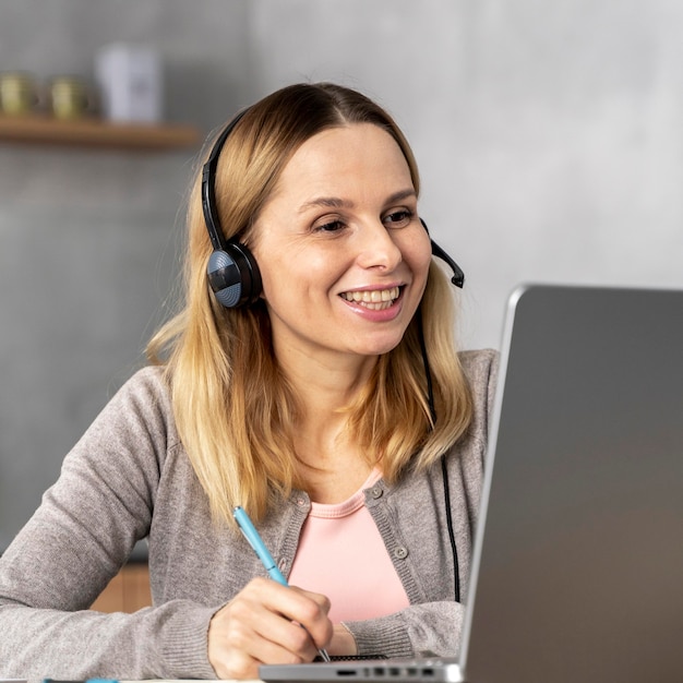 Gratis foto vrouw met hoofdtelefoon die aan laptop werkt