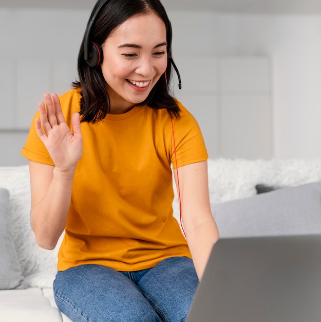 Vrouw met hoofdtelefoon voor videogesprek op laptop