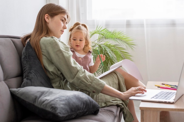 Gratis foto vrouw met jong geitje dat aan laptop werkt