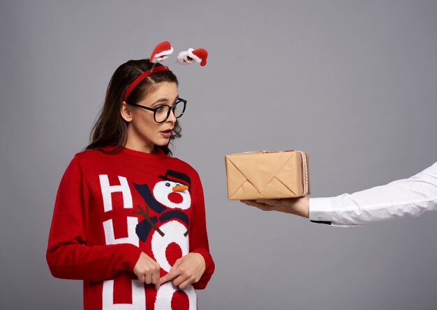 Vrouw met kerstcadeau en grappig gezicht