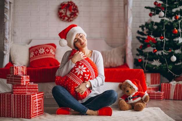 Vrouw met kerstcadeaus door kerstboom