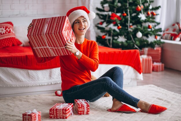 Vrouw met kerstcadeaus door kerstboom