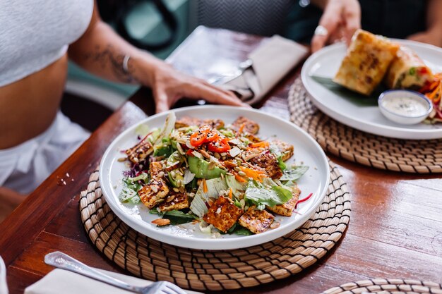 Vrouw met kleurrijke gezonde veganistische vegetarische maaltijdsalade in het natuurlijke daglicht van de zomerkoffie