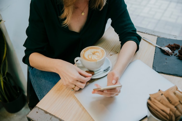 Vrouw met koffie bijsnijden met behulp van smartphone