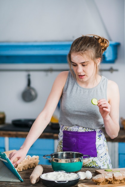 Gratis foto vrouw met komkommer op zoek naar recept in internet