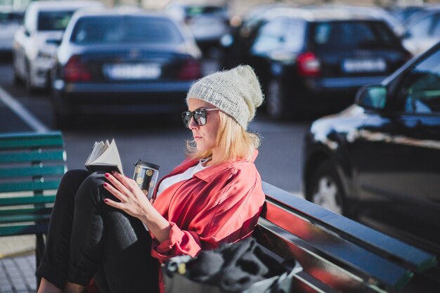 Vrouw met kop leesboek op bankje