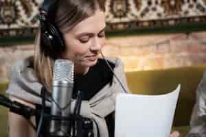 Gratis foto vrouw met koptelefoon die een podcast draait en een microfoon gebruikt