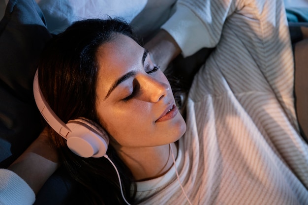 Vrouw met koptelefoon voor muziek thuis in bed