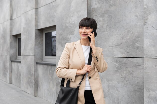 Vrouw met kort haar die buiten aan de telefoon praat