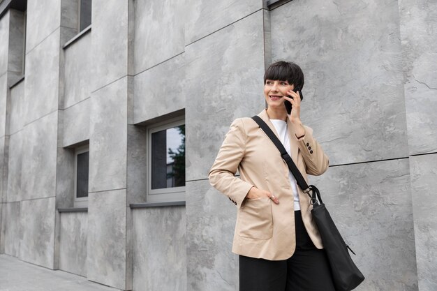 Vrouw met kort haar die buiten aan de telefoon praat.