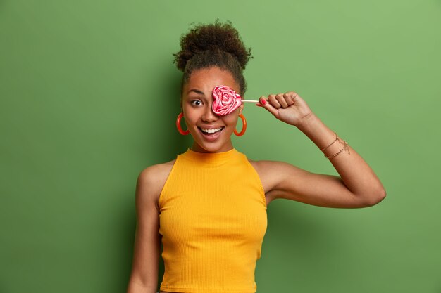 Vrouw met krullend haar behandelt oog met heerlijke geïsoleerde lolly