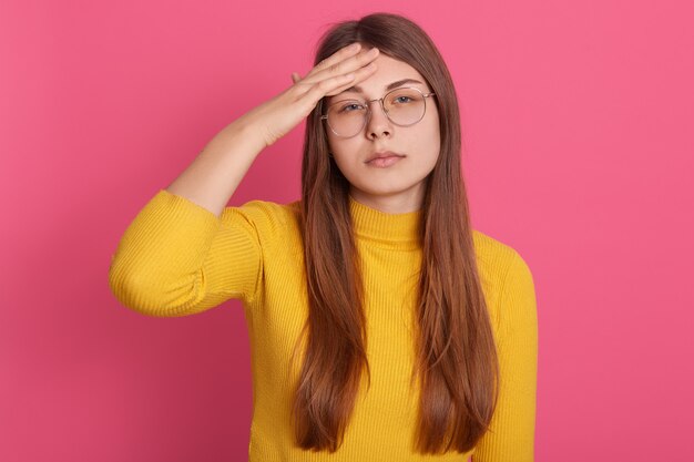 Vrouw met lang mooi haar dat lijdt aan vreselijke hoofdpijn, met een verstoorde uitdrukking, terwijl ze haar handen op haar voorhoofd houdt