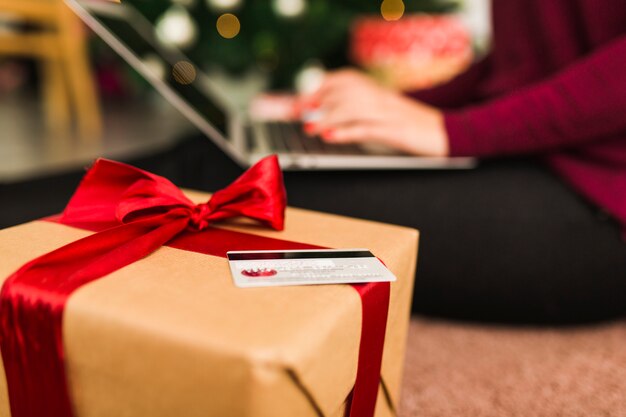 Vrouw met laptop dichtbij creditcard en giftdoos