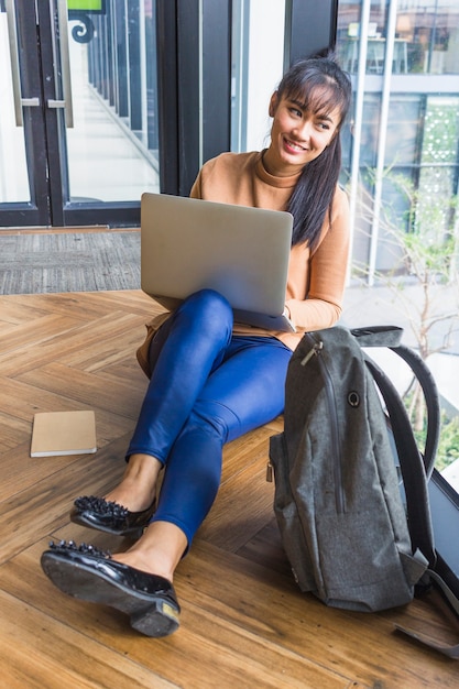 Vrouw met laptop dichtbij rugzak