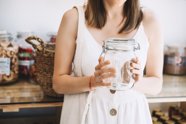Vrouw met lege glazen pot koopt duurzame plastic gratis supermarkt zero waste shop