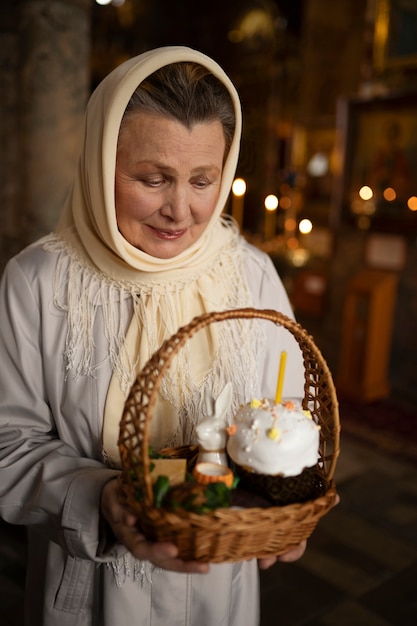 Gratis foto vrouw met mand in de kerk met eten ter viering van grieks pasen