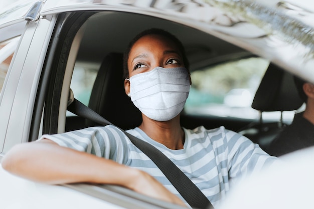 Gratis foto vrouw met masker bij doorrijden met haar auto