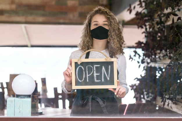 Vrouw met masker met bord met open tekst