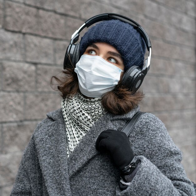 Vrouw met medisch masker in de stad, luisteren naar muziek