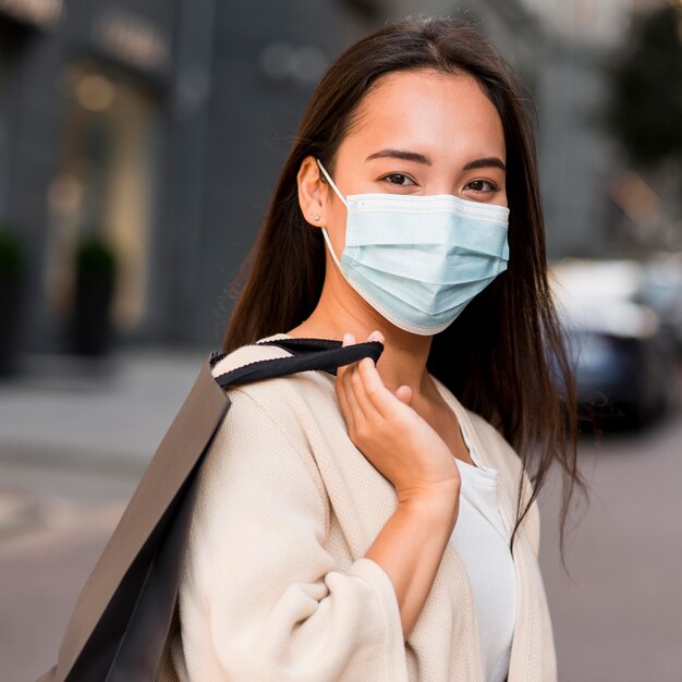 Vrouw met medisch masker uit voor een koopwoede met boodschappentas