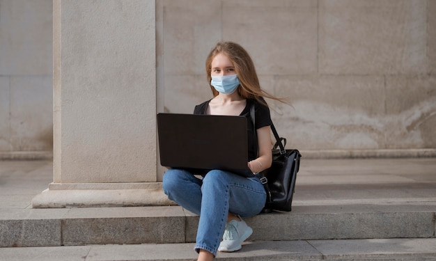 Vrouw met medische masker zittend op trappen buiten