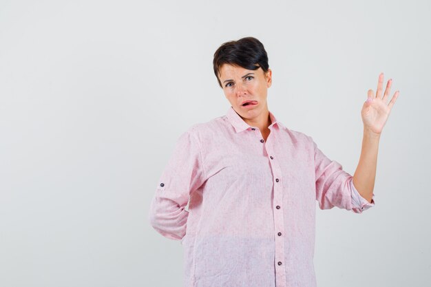 Vrouw met ok gebaar, tong uitsteekt in roze shirt vooraanzicht.