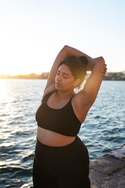 Gratis foto vrouw met overgewicht die buiten traint bij het meer