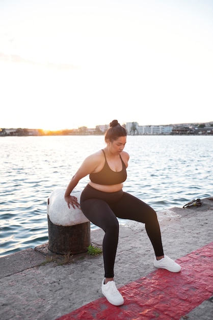 Gratis foto vrouw met overgewicht die buiten traint bij het meer