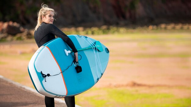 Vrouw met paddleboard aan zee