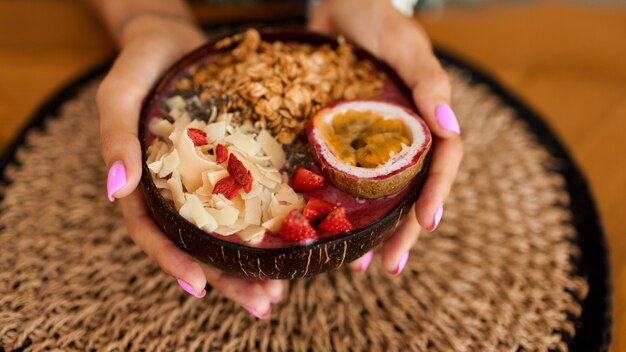 Vrouw met plaat kokosnoot plaat met smakelijke smoothie kom.