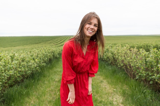 Gratis foto vrouw met rode jurk in veld