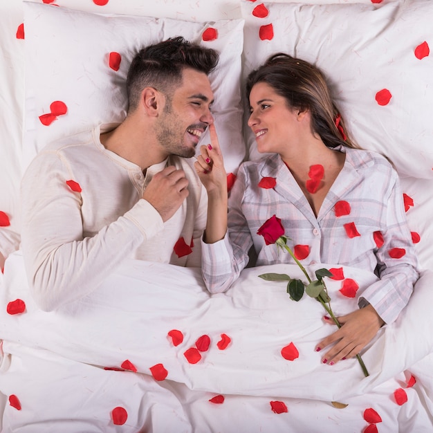 Vrouw met roos aanraken man neus in bed
