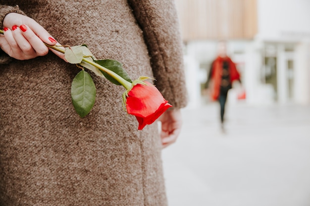 Gratis foto vrouw met roos achter rug