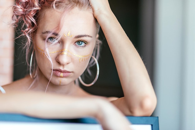 vrouw met roze haar en artistieke make-up in de vorm van penseelstreken die naar de camera kijken. Gezicht kunst concept