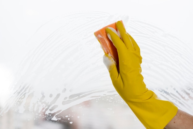 Vrouw met rubberhandschoen schoonmakend venster