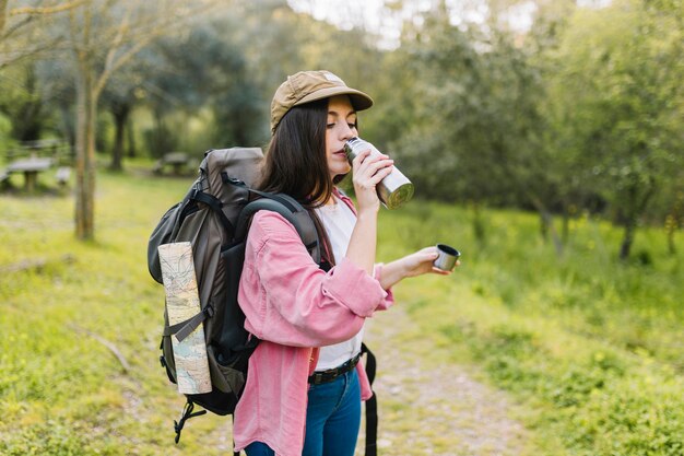 Vrouw met rugzak drinken uit thermos