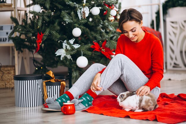 Vrouw met schattig konijntje door kerstboom