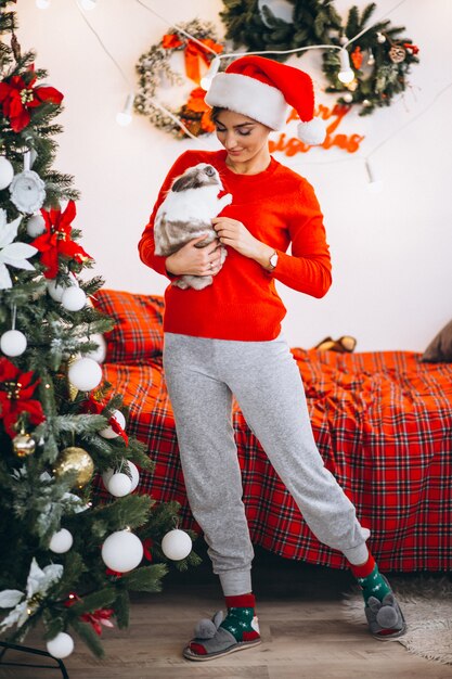 Vrouw met schattig konijntje door kerstboom