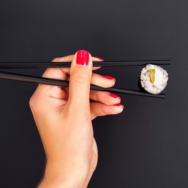 Vrouw met stokjes met sushi roll