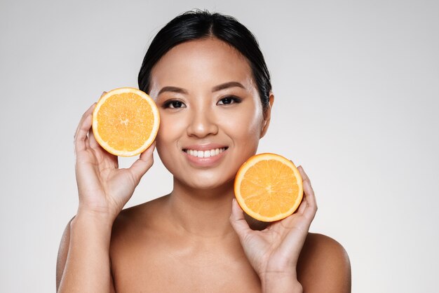 vrouw met stukjes sinaasappel in de buurt van haar gezicht