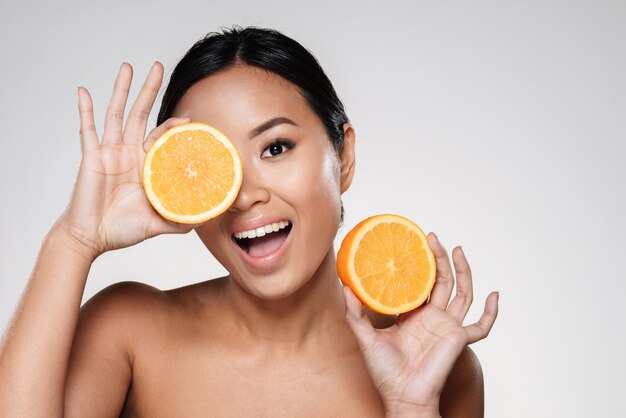 vrouw met stukjes sinaasappel in de buurt van haar gezicht