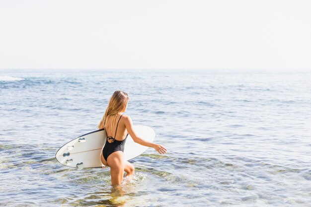 Vrouw met surfplank op het strand