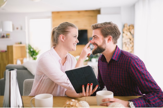 Gratis foto vrouw met tablet wat betreft de neus van de vriend